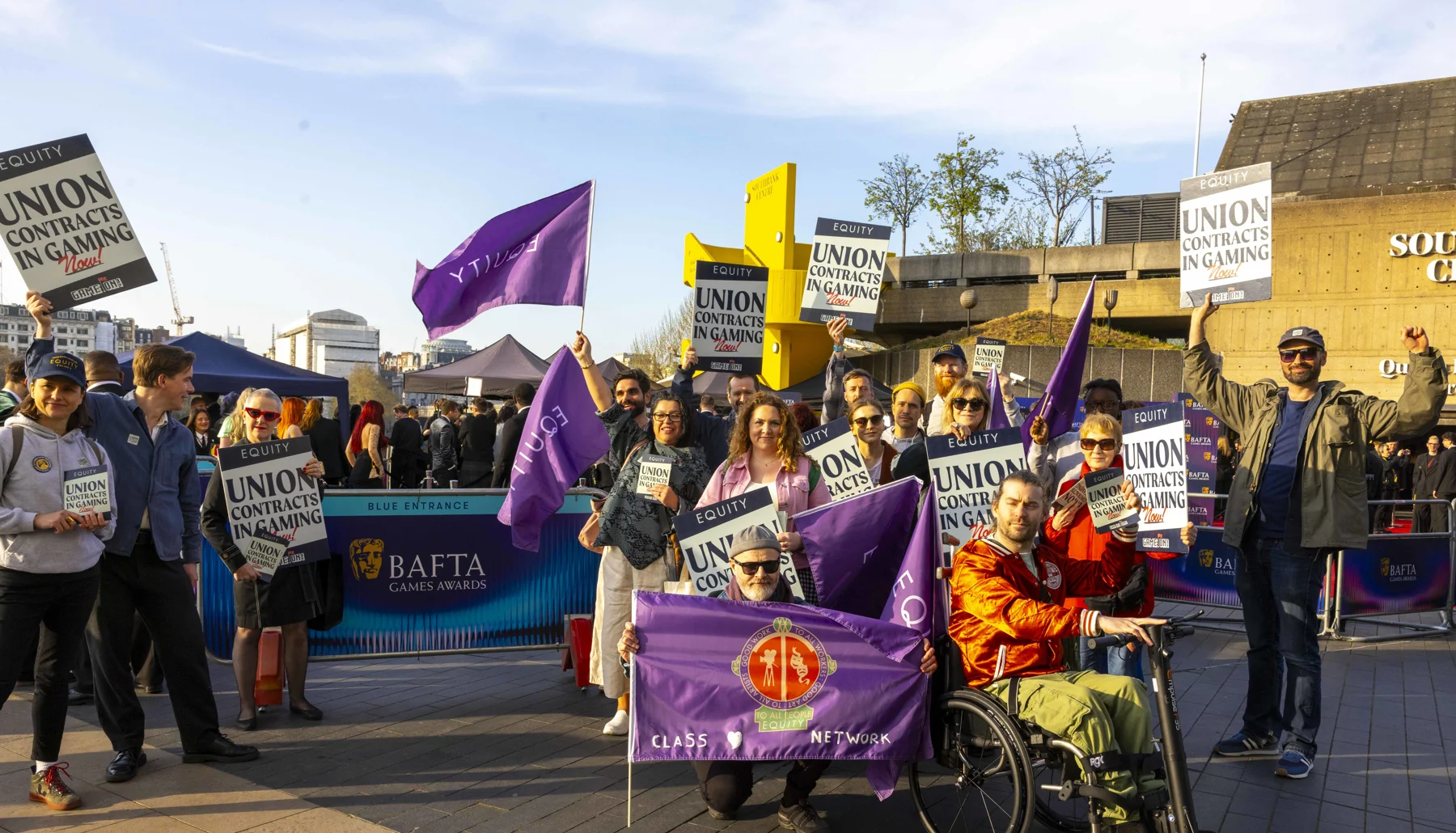 A group of Equity members holding purple Equity flags and Union Contracts in Gaming Now! placards outside the BAFTA game awards